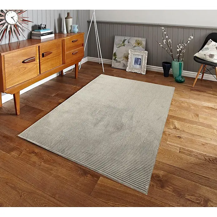 Alfombra de pelo corto Vista - Taupe, 200 x 140 cm, 100% poliéster - Alfombra clara, sutilmente rayada, sobre un suelo de madera en una habitación acogedora.