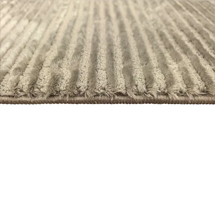 Alfombra de pelo corto Vista - Taupe, 200 x 140 cm, 100% poliéster - Primer plano de una alfombra de felpa beige claro con textura acanalada distintiva, mostrando fibras y borde.