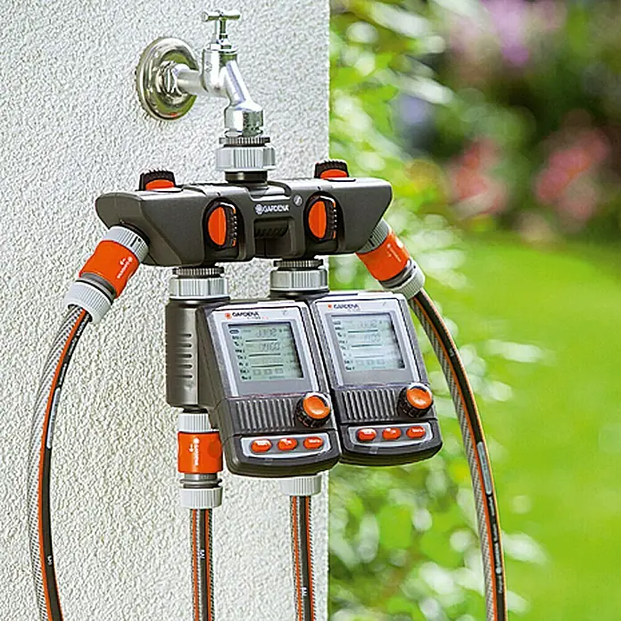 Gardena 4-Wege-Verteiler - Gewindegröße Wasserhahn: 26,5 mm (G 3/4“) - Ein Gardena Wasserverteiler mit zwei Bewässerungscomputern, angeschlossen an einen Wasserhahn und Gartenschläuche.