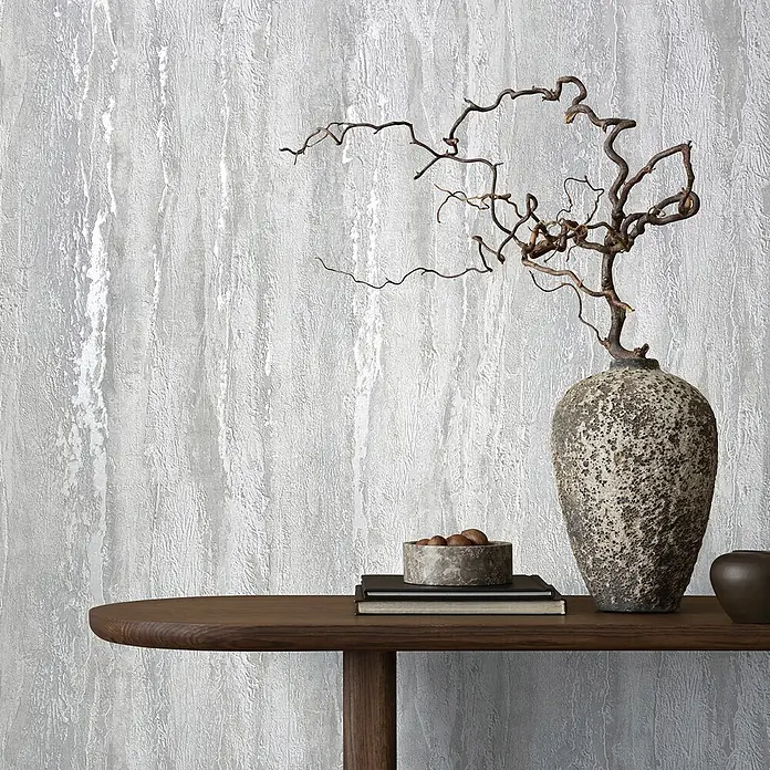 Marburg Papel pintado de vinilo - Gris, Efecto cemento, 10 x 0,53 m - Papel pintado gris texturizado con patrón vertical, exhibido en un interior contemporáneo con mesa de madera.