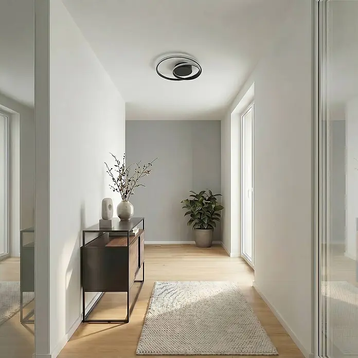 Lindby Deckenleuchte Emisua - schwarz - Moderne Deckenleuchte in Schwarz und Silber mit überlappendem Ringdesign, beleuchtet einen Flur.