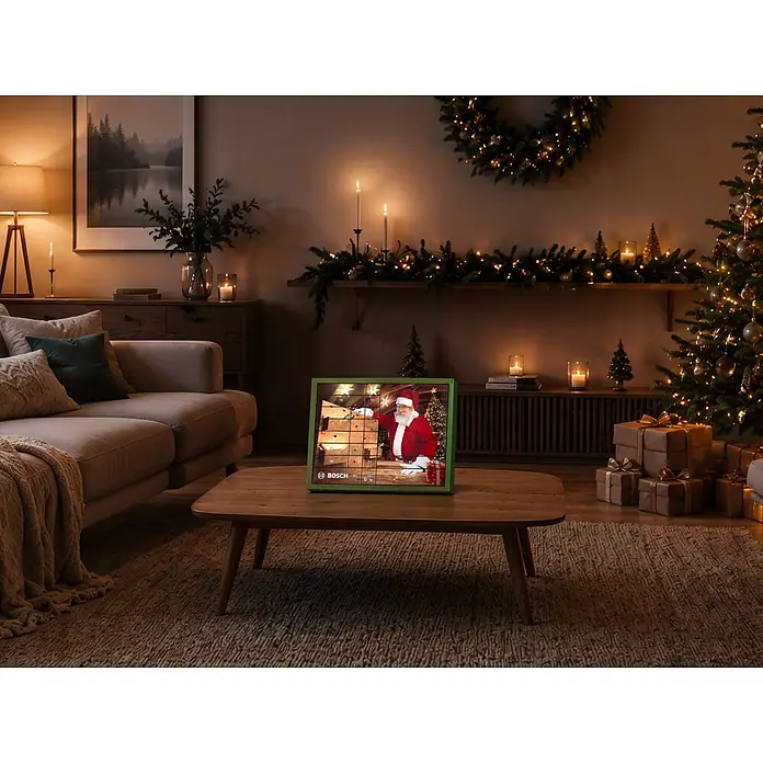 Bosch Adventskalender - Gesamtumfang: 44 -tlg. - Bosch Adventskalender mit grünem Rahmen und Weihnachtsmann auf Kaffeetisch in festlichem Wohnzimmer.