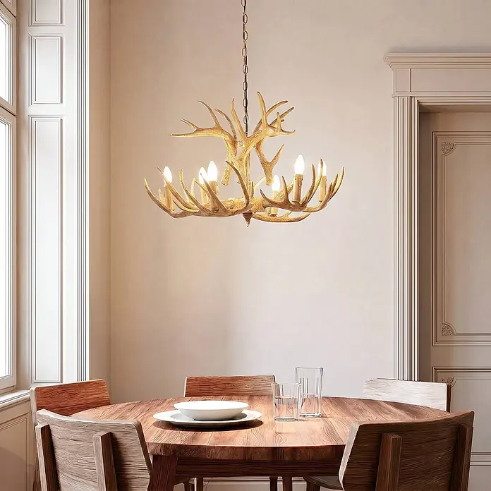 Lindby Pendelleuchte Fibi - braun / rost, braun rustikal, E14 - Goldener Geweih-Kronleuchter beleuchtet einen Essbereich über einem Holztisch mit Stühlen.