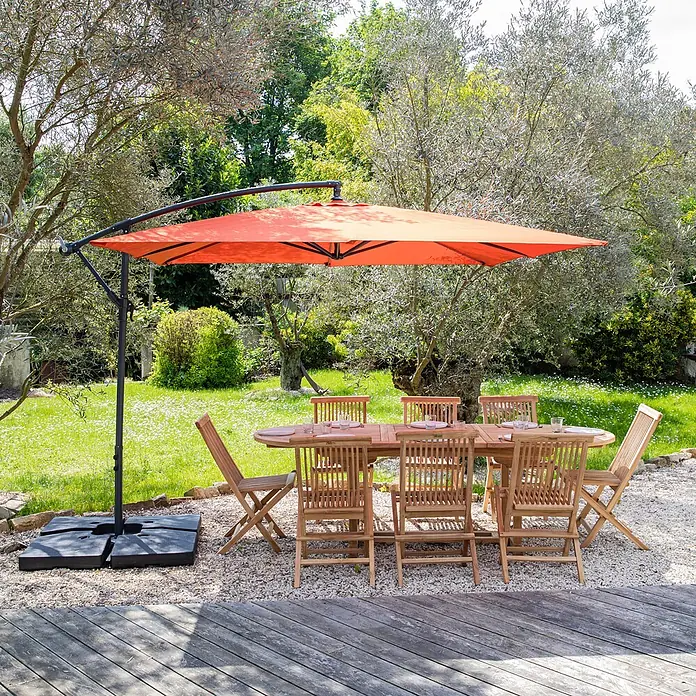 Happy Garden Ampelschirm MOLOKAI - Terracotta - Gartenmöbel-Set aus Holz mit ovalem Tisch und 6 Stühlen, dazu ein großer orangefarbener Ampelschirm auf einer Terrasse.