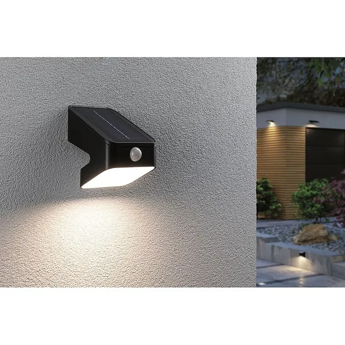 Paulmann Solarleuchte Lesly - Lichtfarbe: Warmweiß, LED, Höhe: 138 mm - Schwarze Solar-Außenwandleuchte mit Bewegungsmelder, beleuchtet eine strukturierte Wand bei Dämmerung. Moderne Gartenbeleuchtung.