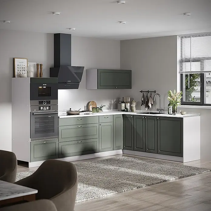 Vicco Eckküche - B x T: 287 x 60 cm, Grün-Gold Landhaus, Ohne Elektrogeräte - Moderne L-förmige Küche mit hell- und dunkelgrünen Schränken, integrierten Geräten, dunkler Dunstabzugshaube, weißen Arbeitsplatten und Fenster.