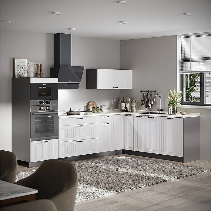 Vicco Eckküche - B x T: 287 x 60 cm, Weiß Landhaus, Ohne Elektrogeräte - Moderne L-förmige Küche mit weißen gerillten Schränken, schwarzen Griffen, heller Arbeitsplatte, integrierten dunklen Geräten und Fenster.