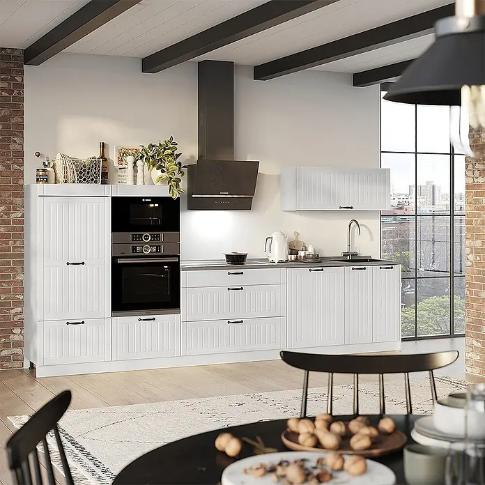Vicco Küchenzeile - Weiß Landhaus, Ohne Elektrogeräte - Weiße Küche mit Lamellenschränken, schwarzen Griffen, integrierten Öfen und einer dunklen Dunstabzugshaube, modern gestaltet.