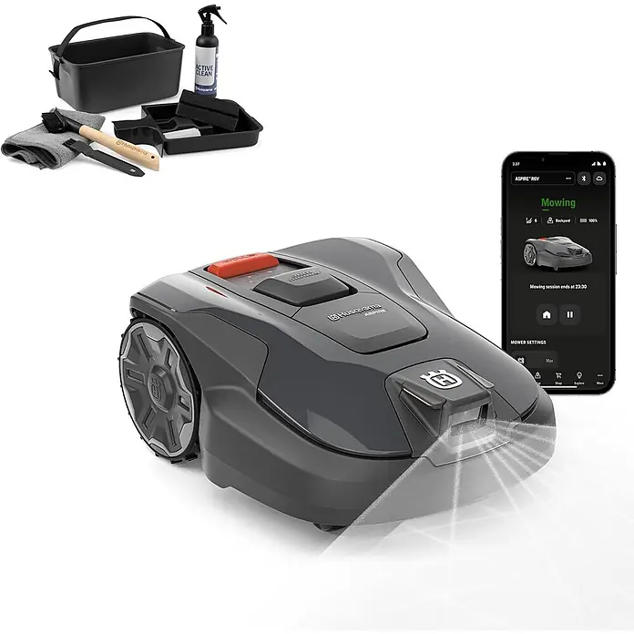 Husqvarna Automower Aspire R6V Mähroboter-Set 600 m² + Cleaning Kit -  - Dunkelgrauer Husqvarna Mähroboter mit orangefarbenem Stoppknopf, beleuchtetem Frontlicht, abgebildet mit schwarzem Reinigungsset und Smartphone mit Mähroboter-App.