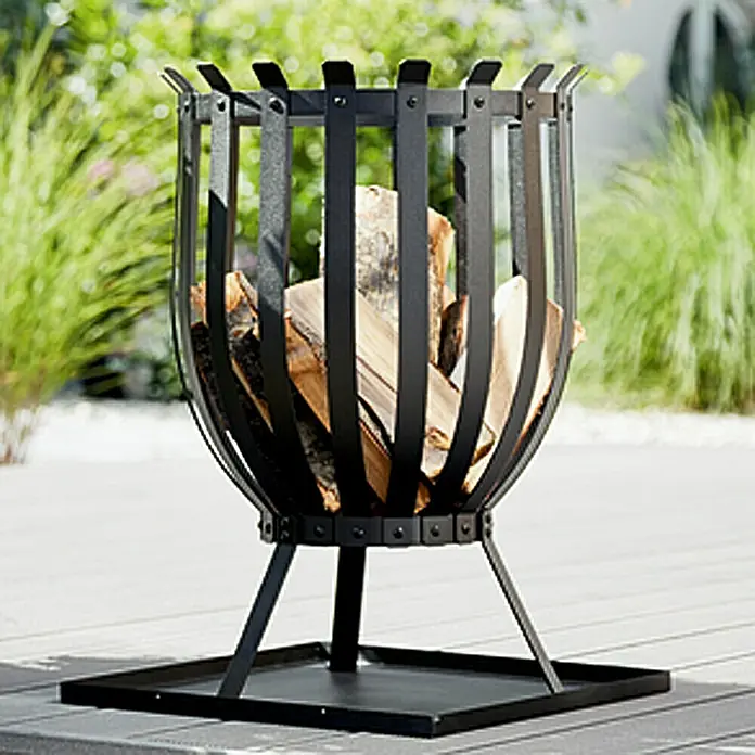 Grillstar Grill-Feuerkorb Reno - Schwarz, Durchmesser: 35 cm - Eine moderne Feuerstelle aus schwarzem Metall, gefüllt mit Holzscheiten, steht im Garten. Sie bietet Wärme und Atmosphäre für gemütliche Abende.