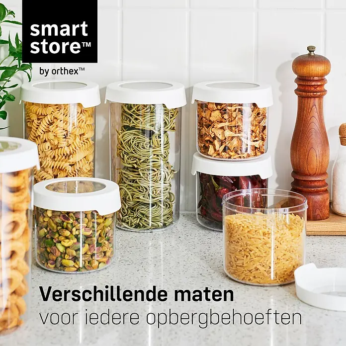 SmartStore Vorratsdose Vision - L x B x H: 12,5 x 9 x 28 cm, Kunststoff, Weiß - Transparente Smart Store by Orthex Vorratsdosen mit weißen Deckeln, gefüllt mit verschiedenen Trockenlebensmitteln wie Nudeln und Nüssen, auf einer Küchentheke.
