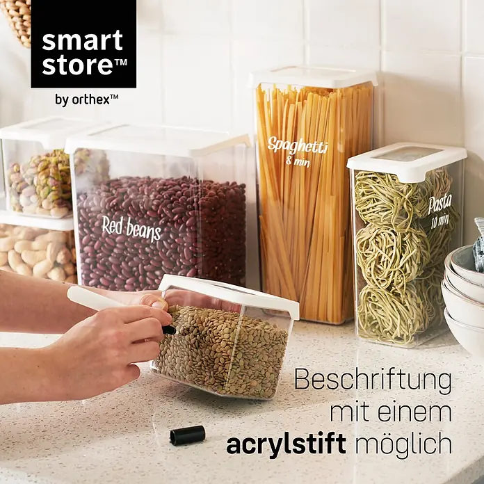 SmartStore Vorratsdose Vision - Ø x H: 11,5 x 10 cm, Kunststoff, Weiß - Transparente, rechteckige Vorratsdosen mit weißen Deckeln. Eine Hand beschriftet eine Dose, um die Eignung für Acrylstifte zu zeigen.