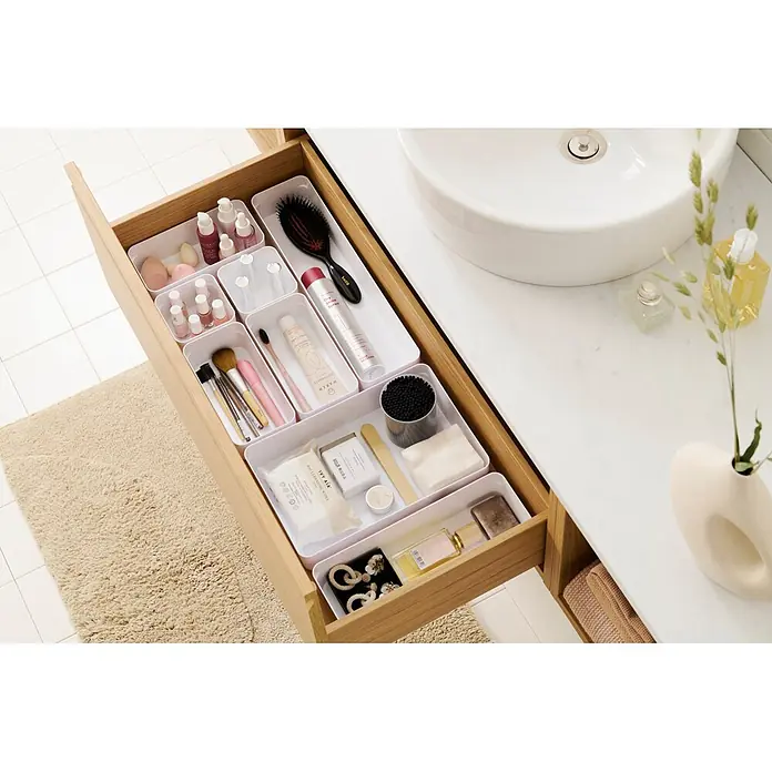 SmartStore Vorratsdose Compact Sort - L x B x H: 10 x 29,5 x 6 cm, Kunststoff, Weiß - Eine offene Badezimmerschublade mit weißen Organizern, die verschiedene Toilettenartikel und Kosmetika ordentlich aufbewahren.