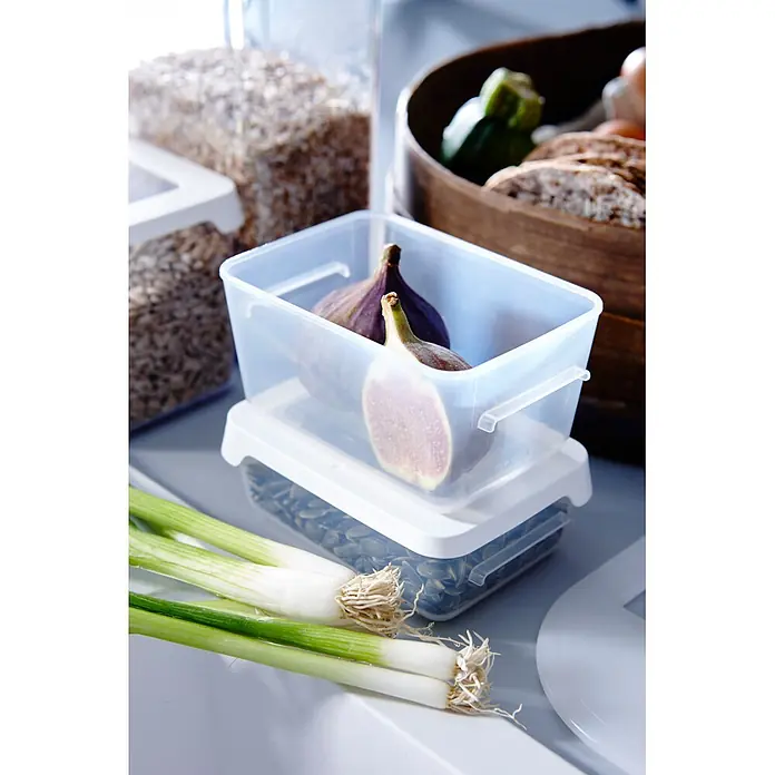 SmartStore Vorratsdose Snack - L x B x H: 12,5 x 9,5 x 4,5 cm, Kunststoff, Weiß - Klare Kunststoff-Vorratsbehälter, teils gestapelt, mit Feigen und Samen, umgeben von frischem Gemüse wie Frühlingszwiebeln und Brot.
