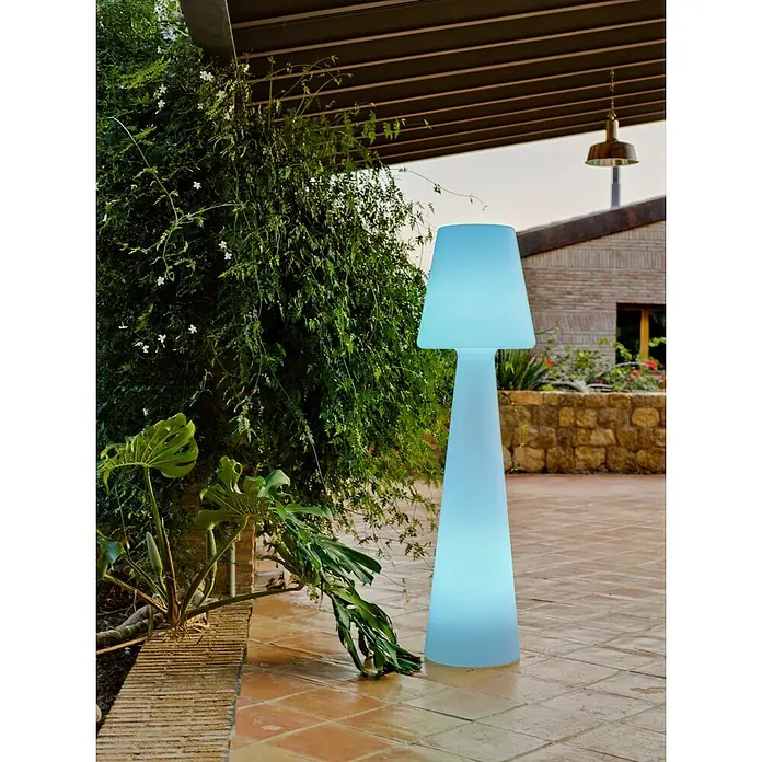 New Garden Lámpara de pie con batería Lola 165 Blanco - Blanco, Altura: 165 cm, RGB - Lámpara de pie exterior azul claro brillante en un patio con plantas.