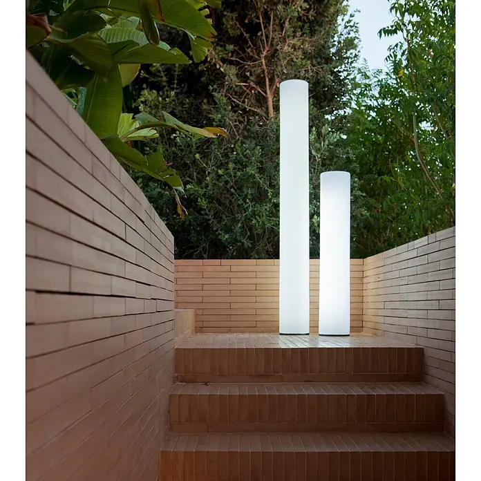 New Garden Lámpara de diseño para exterior Fity 100 - 9,5 W, Blanco, Ø x Al: 19 x 100 cm, RGB - Dos lámparas cilíndricas de exterior altas e iluminadas sobre una escalera de azulejos en un jardín.