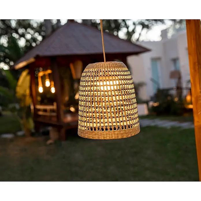 New Garden Lámpara colgante LED recargable Positano 35 - 9 W, Marrón, Ø x Al: 33 x 35 cm, Blanco cálido - Linterna colgante tejida iluminada en un jardín exterior al anochecer. La luz cálida crea un ambiente acogedor.