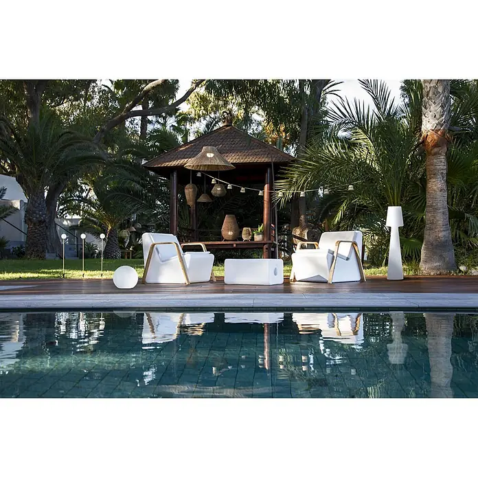 New Garden Lámpara de pie con batería Niza 230 - Marrón, 155 x 80 x 230 cm, Blanco cálido - Tumbonas blancas de exterior, una mesa rectangular y lámparas modernas junto a una piscina y glorieta en un jardín exuberante.