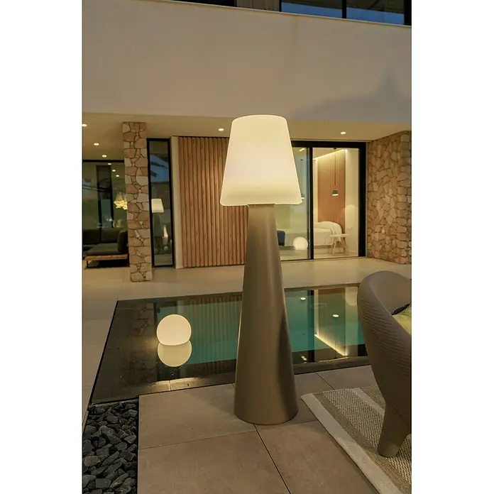 New Garden Lámpara de pie con batería Lola 165 Taupe - Taupe, Altura: 165 cm, Blanco neutro - Lámpara de pie exterior alta con base cónica gris y pantalla luminosa blanca, iluminando un patio moderno junto a una piscina.