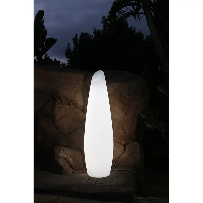 New Garden Lámpara de pie con batería Fredo 140 - 1,3 W, Blanco, Ø x Al: 38 x 139 cm, RGB - Lámpara de exterior blanca brillante con diseño alto y curvo, iluminando un jardín oscuro por la noche.
