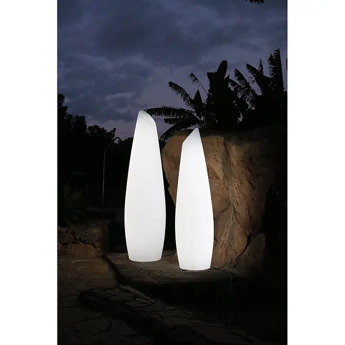 New Garden Lámpara de pie para exterior Fredo 140 - 18 W, Blanco, Ø x Al: 38 x 139 cm, Blanco cálido - Dos lámparas de exterior altas, blancas e iluminadas con forma abstracta, que proporcionan luz ambiental en un jardín oscuro.