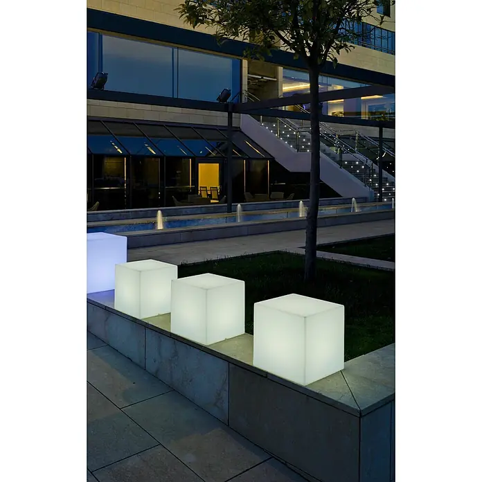 New Garden Lámpara solar Cuby 40 LED - 1 W, Blanco, Color de luz: RGBW, L x An x Al: 40 x 40 x 40 cm - Asientos cúbicos iluminados en un patio moderno, uno azul brillante, proporcionando luz ambiental.
