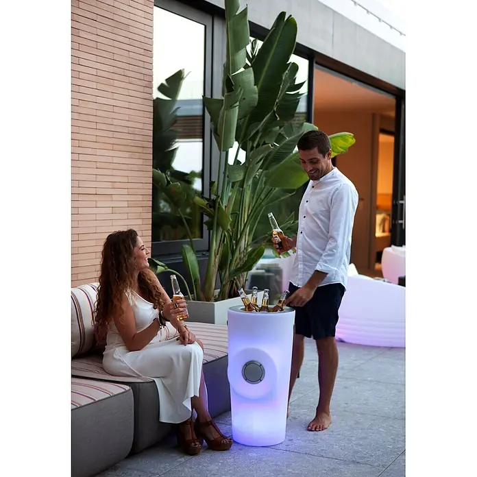 New Garden Lámpara para exterior Woody 70 - Blanco, 38 x 36 x 70 cm, RGB, Altavoz Bluetooth - Nevera y altavoz LED de exterior, de color morado, con botellas de cerveza, utilizado por una pareja en un patio.