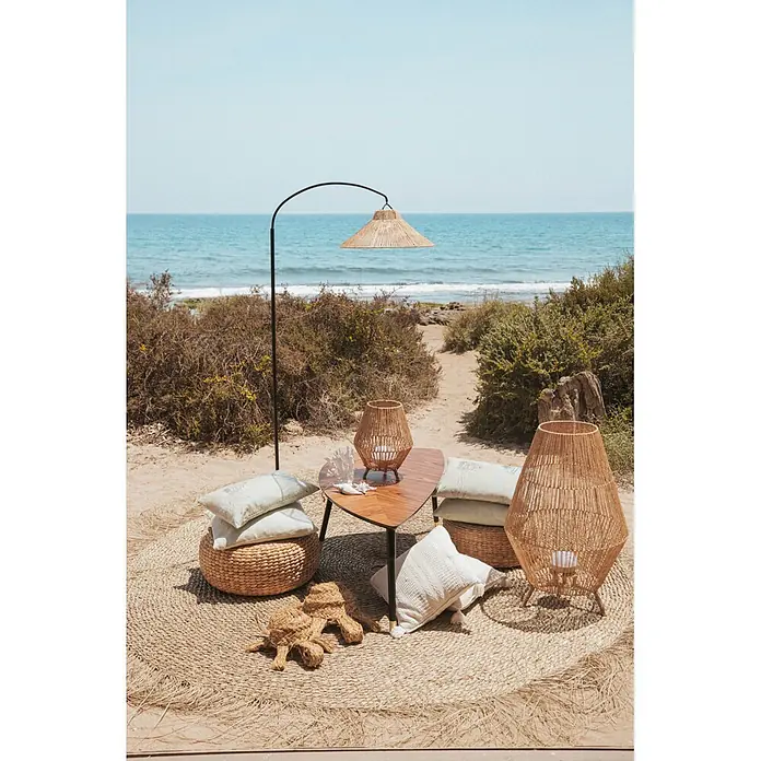 New Garden Lámpara de pie con batería Niza 165 - Marrón, 73 x 40 x 167 cm, Blanco cálido - Salón exterior con lámparas tejidas naturales, pufs y cojines en una playa. Mar de fondo.