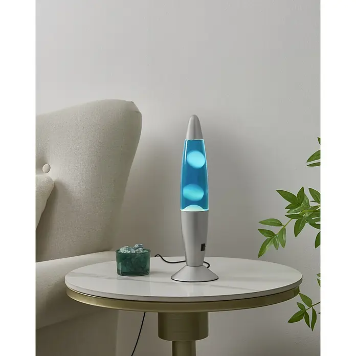 Eglo Tischleuchte - 2,2 W, Ø x H: 105 x 360 mm, Farbe Gehäuse: Blau/ Weiß - Silberne Lavalampe mit blauer Flüssigkeit und Wachs, auf einem weißen Beistelltisch neben einem cremefarbenen Sessel.