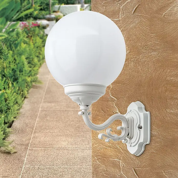 Orion Leuchten Außenwandleuchte Reika - 60 W, Weiß, Opal, IP43 - Weiße kugelförmige Außenwandleuchte mit kunstvoller Halterung, an einer strukturierten Wand neben einem Gartenweg montiert.
