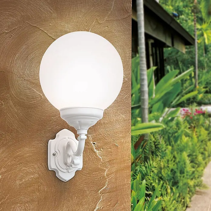Orion Leuchten Außenwandleuchte Reika - 60 W, Weiß, Opal, IP43 - Weiße Kugelleuchte für den Außenbereich mit verziertem Gestell, an einer strukturierten Wand neben tropischem Grün.
