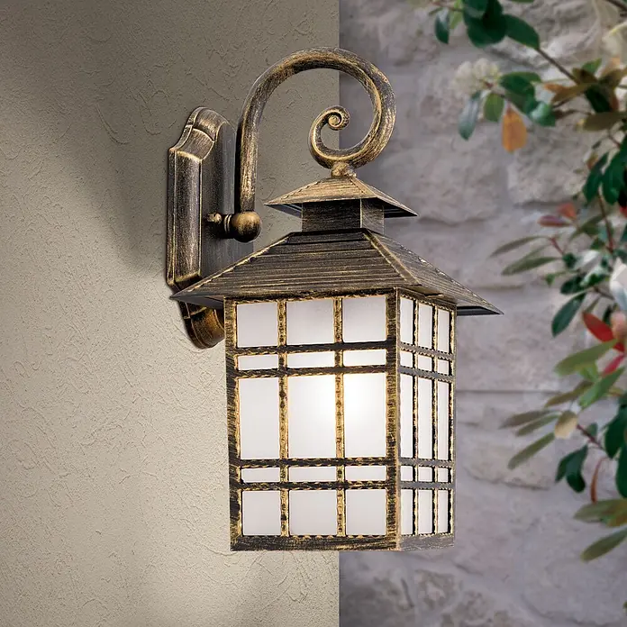 Orion Leuchten Außenwandleuchte Kiko - 60 W, Braun, Matt, IP44 - Eine verzierte Wandlaterne aus Altbronze mit Milchglasscheiben, an einer strukturierten Wand montiert, warm leuchtend.