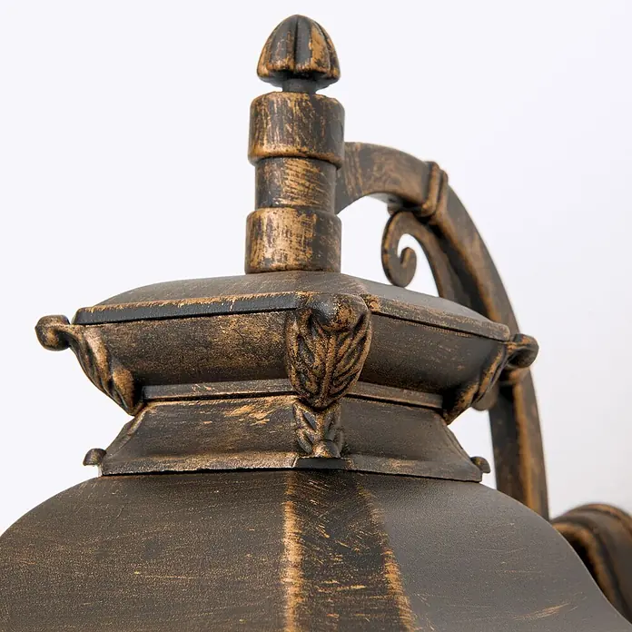 Orion Leuchten Außenwandleuchte Aiko - 60 W, Braun, Matt, IP23 - Nahaufnahme einer Außenlaterne in Antikbronze mit dekorativen Ranken- und Blattmotiven.
