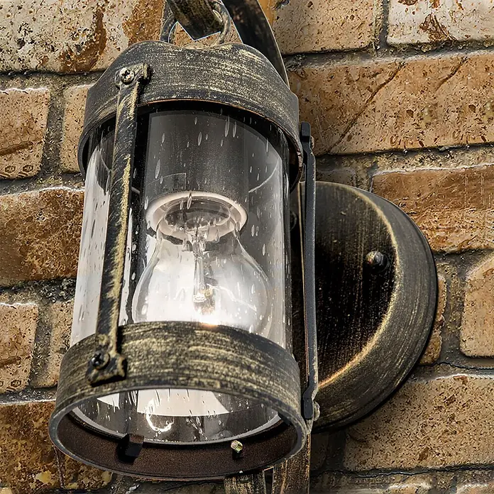 Orion Leuchten Außenwandleuchte Taverna - 60 W, Schwarz, Klar, IP23 - Rustikale bronzefarbene Außenwandleuchte mit klarem, blasigem Glas und sichtbarer Glühbirne, an einer Ziegelwand montiert.