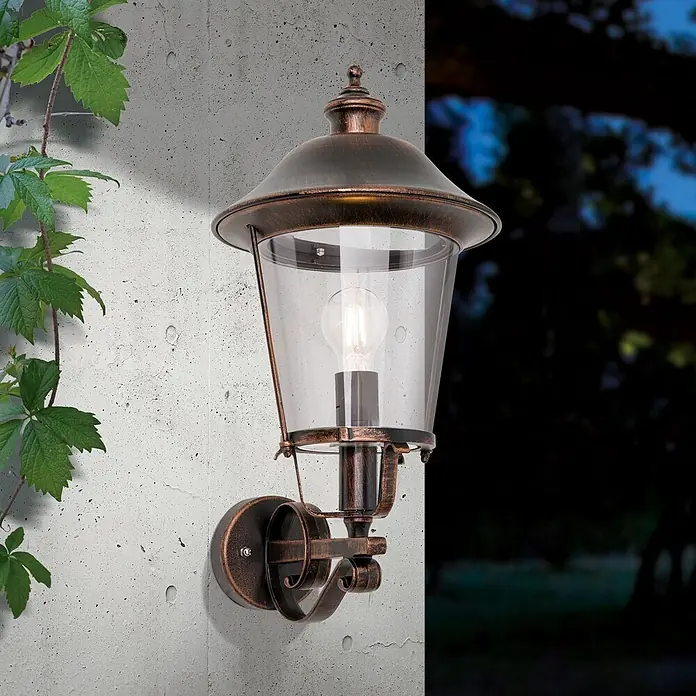 Orion Leuchten Außenwandleuchte Kenzo - 60 W, Schwarz, Klar, IP44 - Eine antike bronzefarbene Außenwandleuchte mit klarem, blasigem Glas und einer sichtbaren Glühbirne, an einer Betonwand montiert.