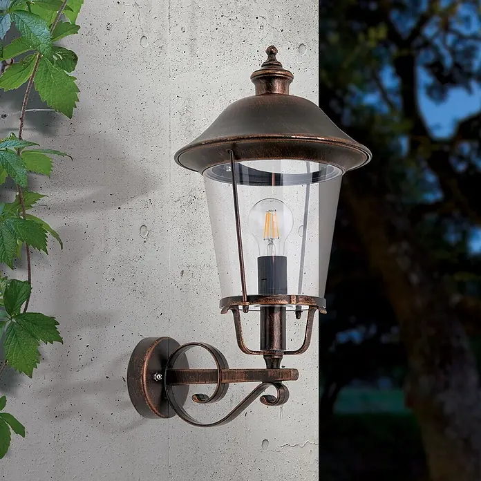 Orion Leuchten Außenwandleuchte Kenzo - 60 W, Schwarz, Klar, IP44 - Außenwandleuchte in dunkler Bronzeoptik mit klarem Glasschirm und sichtbarer LED-Glühlampe, an einer Außenwand montiert.
