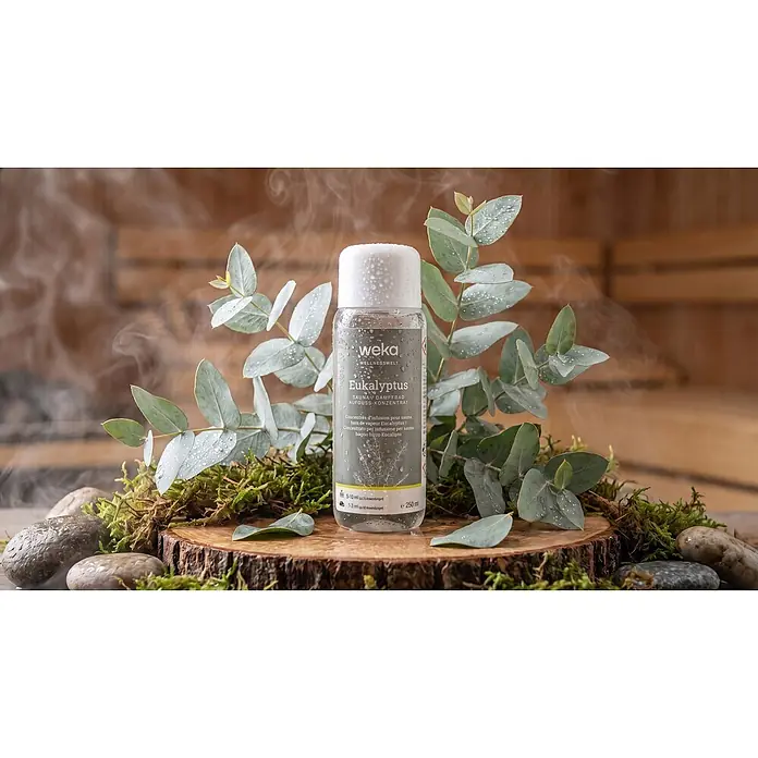 Weka Saunaduft - Duft: Eukalyptus, 250 ml - Transparente Flasche weka Eukalyptus Sauna-Konzentrat mit weißer Kappe, umgeben von Eukalyptusblättern und Dampf, in einer entspannenden Spa-Umgebung.