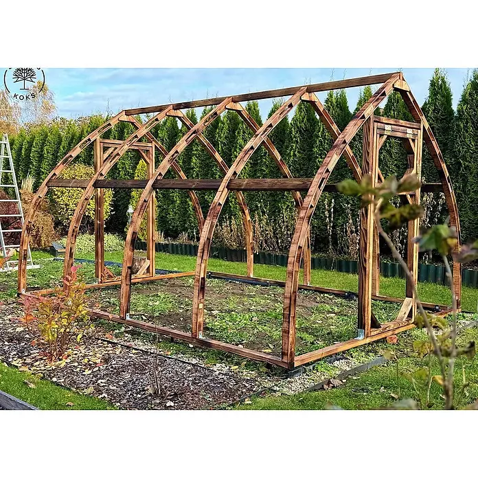 Garten Dream Gewächshaus Arched Wood - Außenmaß inkl. Dachüberstand (B x T): 300 x 400 cm, Material Seitenwand: Kunststoff, 4 mm, Braun - Ein stabiles, dunkelbraunes Holzgewächshausgestell steht bereit im Garten mit gewölbter Struktur und Eingang.