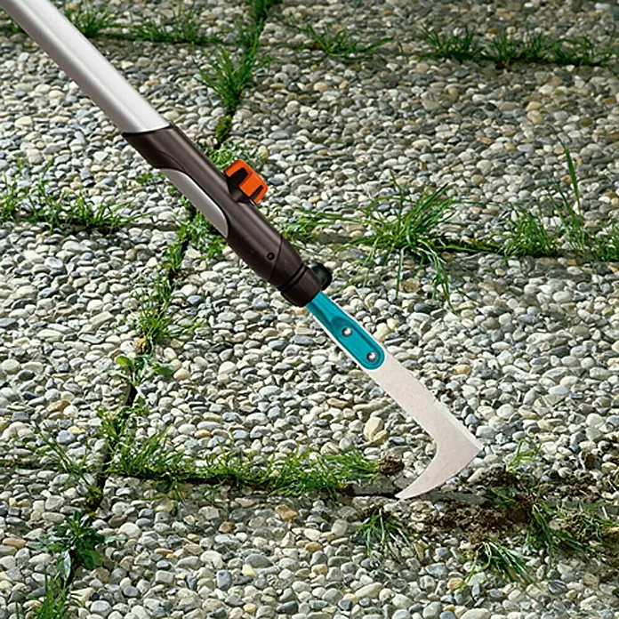 Gardena Combisystem Fugenkratzer - Material Gerätekopf: Stahl, Mit Stiel - Nahaufnahme eines Gardena Fugenkratzers, der Unkraut aus Pflastersteinen entfernt.