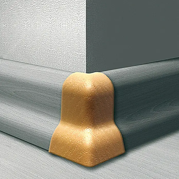 LOGOCLIC Außenecke K40 - Buche, 2 Stk., Geeignet für: Sockelleiste K40 - Detailansicht einer goldenen Sockelleiste Eckabdeckung, die an einer grauen Fußleiste und einer weißen Wand angebracht ist.