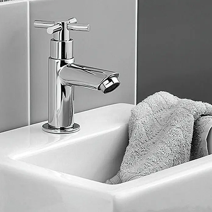Camargue Kaltwasser-Standventil Alba/Padua - Chrom, Glänzend - Nahaufnahme eines stilvollen, verchromten Wasserhahns auf einem weißen Waschbecken mit einem grauen Handtuch.