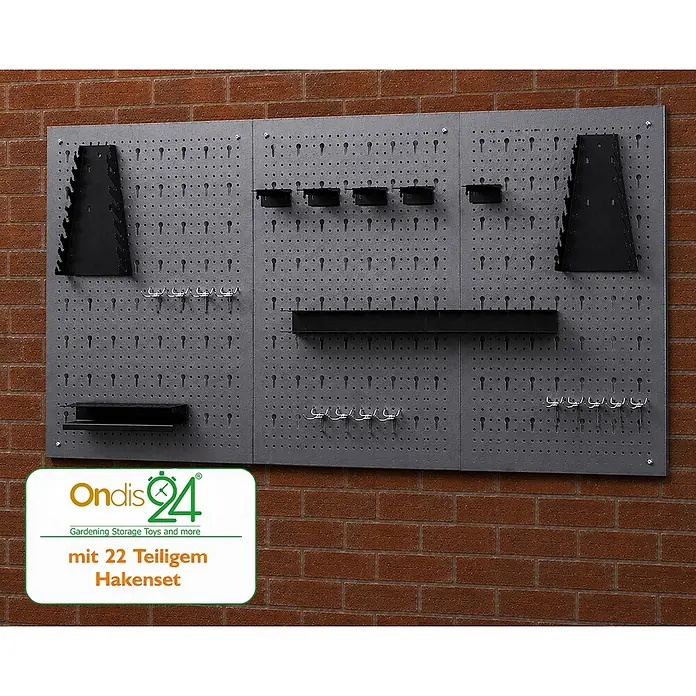 Ondis24 Werkbank-Set - Arbeitshöhe: 850 mm, Metall - Dunkelgraue Metall-Lochwand an Ziegelwand mit schwarzen Haltern und silbernen Haken.