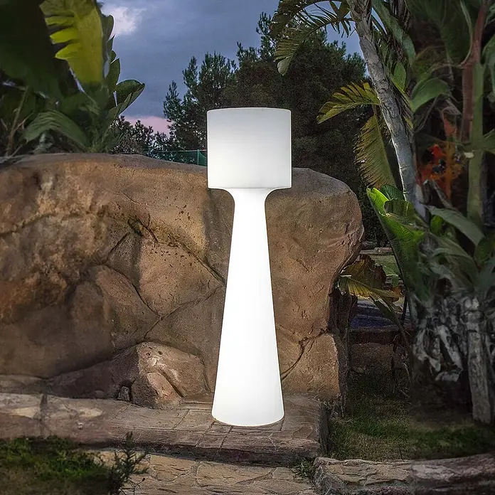 New Garden Lámpara de pie para exterior Grace 140 - Blanco cálido, Con bombillas - Lámpara de pie exterior blanca y luminosa con pantalla rectangular y base cónica, ubicada en un jardín al anochecer.