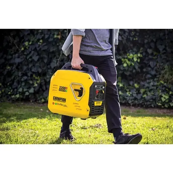 Champion Power Equipment Stromerzeuger 2200 Watt DualFuel Inverter Stromerzeuger Champion MightyAtom 2200 - Nennleistung: 1,9 kW, Tankvolumen: 4 l - Person trägt einen tragbaren gelben Champion 2200W Inverter-Generator im Freien.