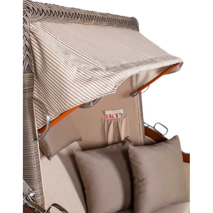 Mr. Deko Strandstuhl Strandkorb Düne Grande Bullauge Mahagoni PE Grey Dessin 510 - Teakholz. Polyrattan, Rückenlehne verstellbar, Beige - Detailaufnahme des Innenraums eines Strandkorbs mit gestreifter Markise, geflochtenem Rahmen und taupefarbenen Kissen.