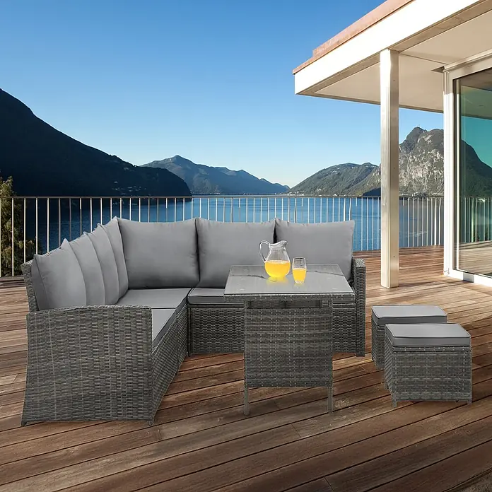 SVITA Loungemöbel-Set MONROE - 4 -tlg., Polyrattan, Grau - Graues Rattan-Gartensofa-Set mit Tisch und zwei Hockern, Kissen inklusive, auf einer Terrasse.