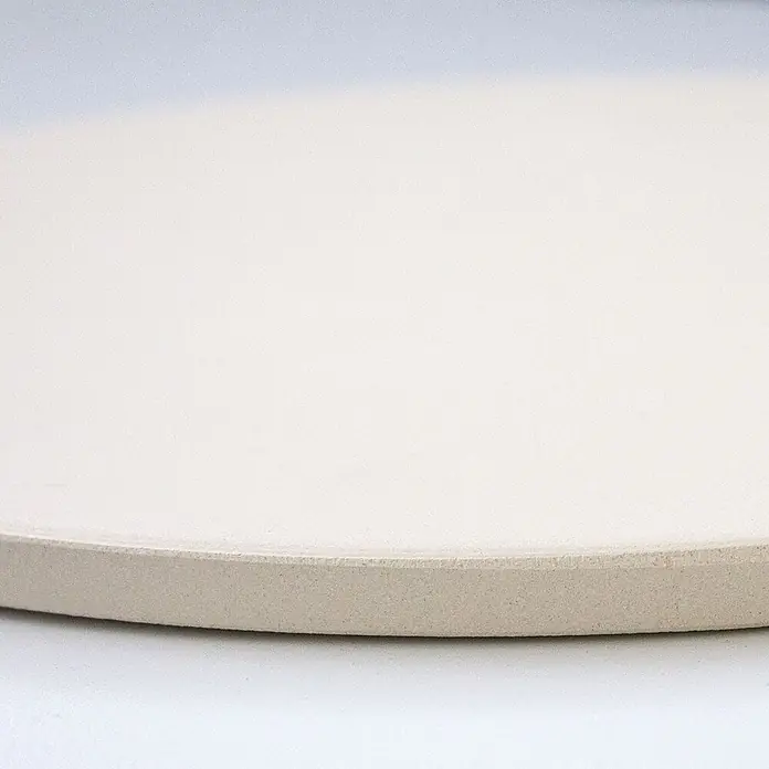 TAINO Pizzastein - L x B: 30 x 30 cm, Durchmesser: 30 cm, Cordierit - Runde hellbeige Keramik-Pizzastein, schräg von der Seite gesehen.