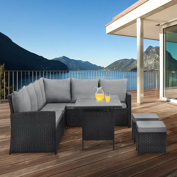 SVITA Loungemöbel-Set MONROE - 4 -tlg., Polyrattan, Schwarz - Schwarze Rattan-Gartenlounge mit grauen Kissen, passendem Tisch und zwei Hockern auf einer Holzterrasse mit Seeblick.
