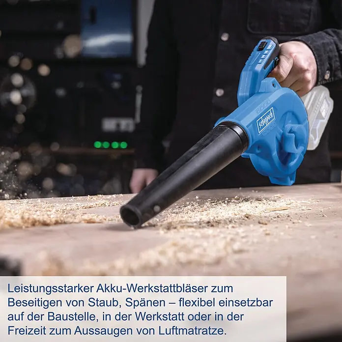 Scheppach IXES 20V Akku-Gebläse C-WBL180-X - 20 V, Ohne Akku - Eine Person benutzt einen blauen Scheppach Akku-Werkstattbläser, um Holzspäne von einer Werkbank zu entfernen.