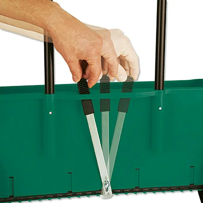 Gardol Carro esparcidor ST 451 - 12 l, Plástico - Primer plano de una sembradora verde con una mano accionando una palanca negra para controlar la siembra.